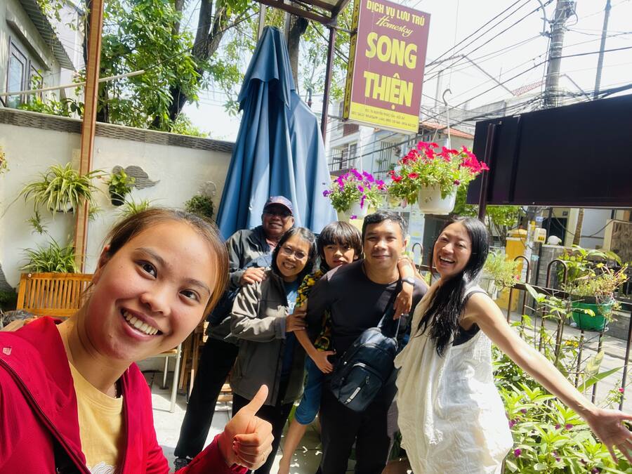 A group of people standing in front of a building with a sign that reads "SONG THIEN".