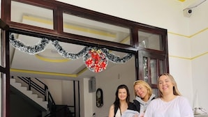 A reception area with a staircase, a wooden bench, and a decorative wreath. - Homestay Song Thien (Da Nang)