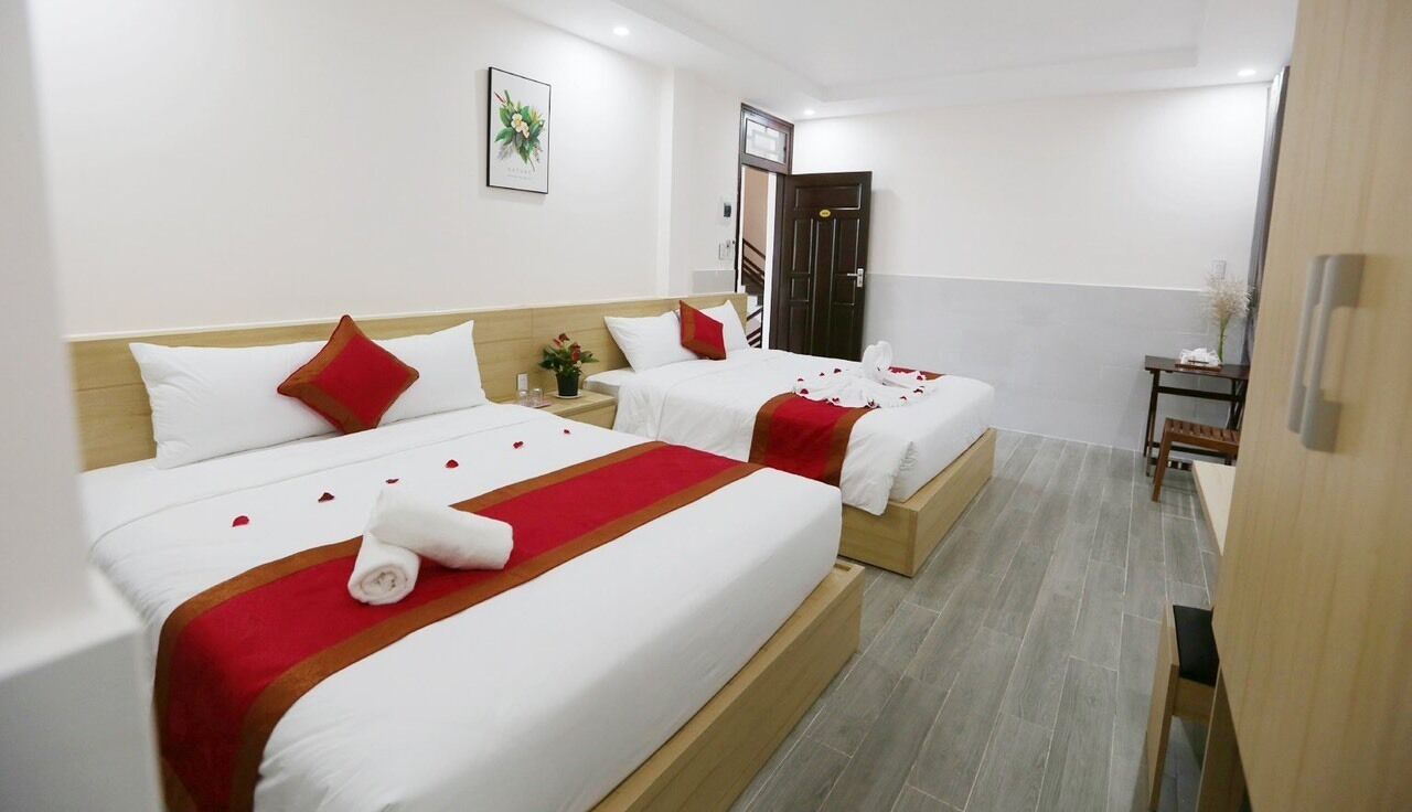 Een hotelkamer met twee bedden, een tafeltje, een nachtkastje en een deur.