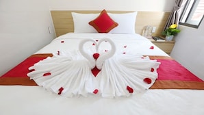 A neatly made bed with a heart-shaped towel arrangement and rose petals. - Homestay Song Thien (Da Nang)