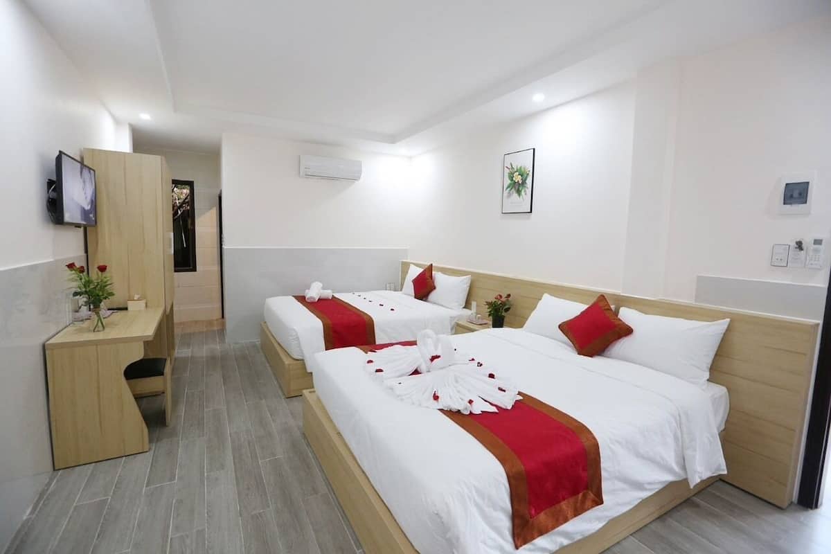 A hotel room with two beds, a desk, and a TV.