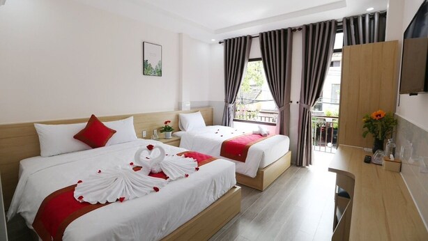 A hotel room with two beds, a balcony, a TV, and a small kitchenette. - Homestay Song Thien (Da Nang)