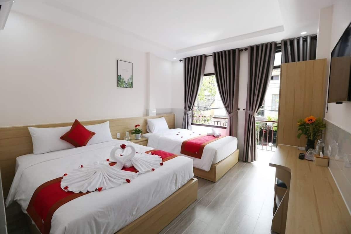 A hotel room with two beds, a balcony, a TV, and a small kitchenette.