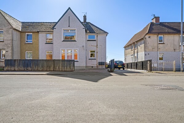A residential street with houses, a motorbike, and a car parked on the side.