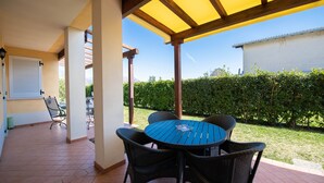 A covered patio with a round table and four chairs, a door, and a window. - Appartamento Golf Resort (Manerba del Garda)