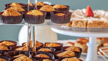 A multi-tiered display of muffins and pastries on a glass stand.