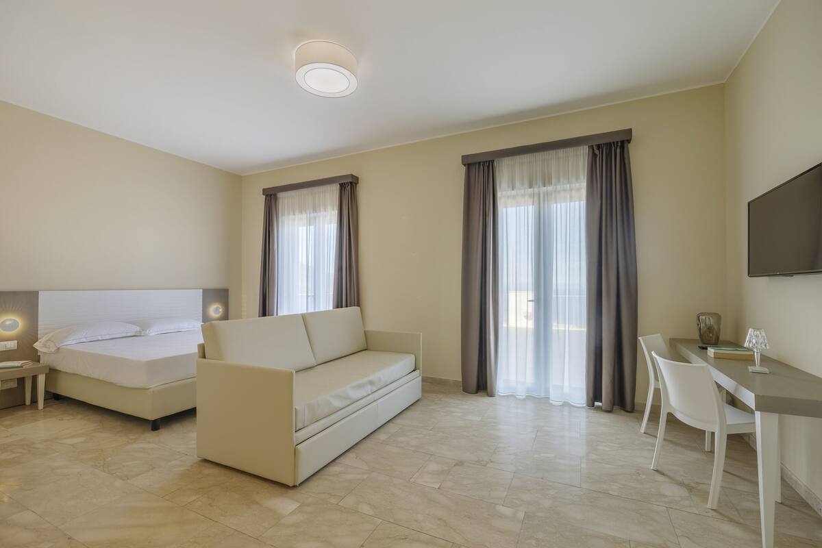 Una habitación de hotel con cama, sofá, escritorio y televisor.