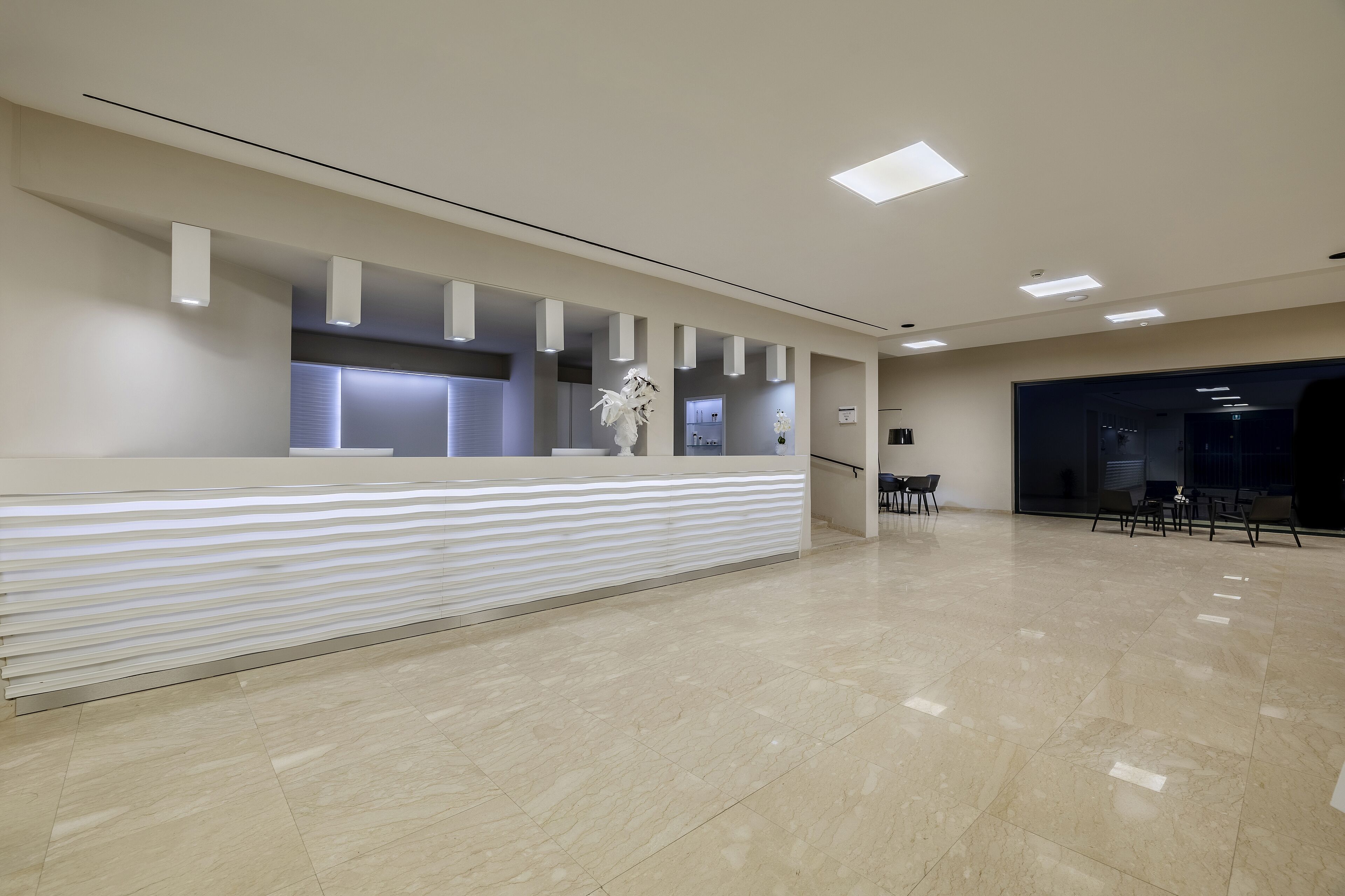 A modern reception area with a reception desk, a potted plant, and a seating area with chairs.