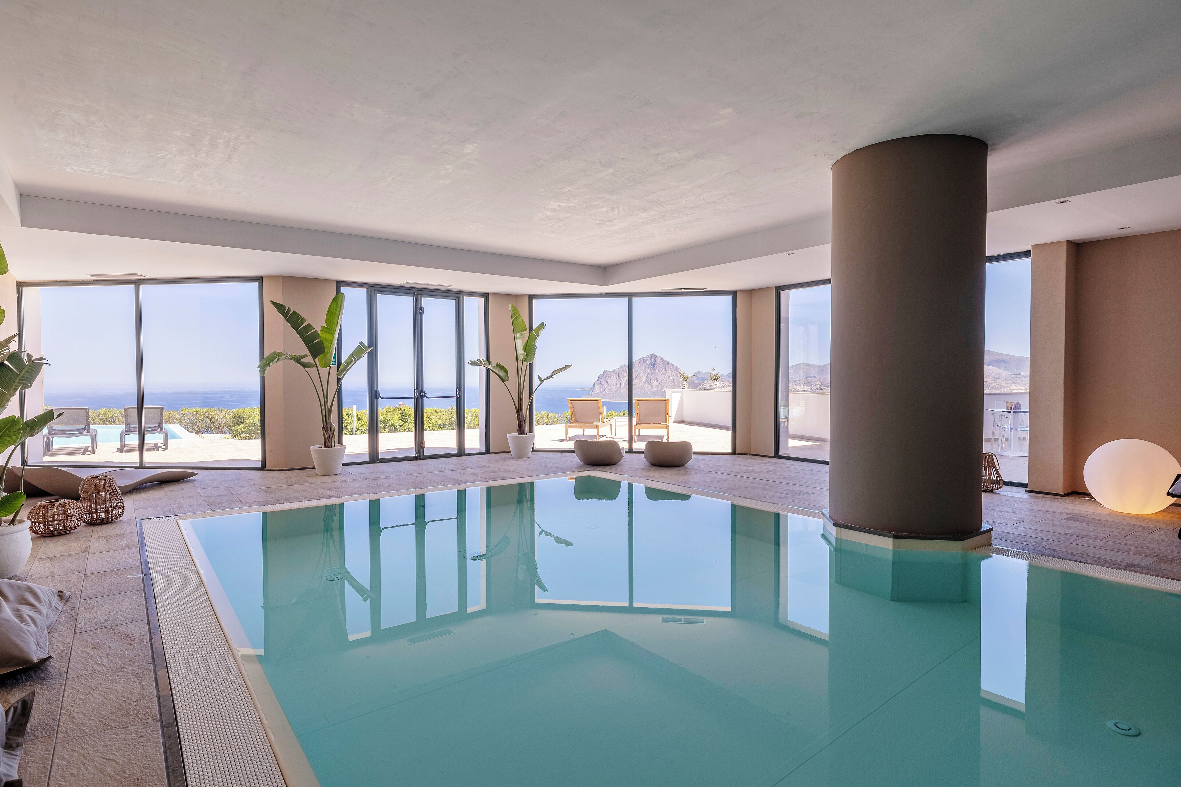 A modern indoor swimming pool with large windows offering ocean views.