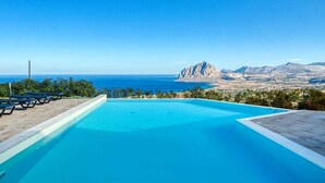 A clear blue pool with a view of the ocean and a mountain in the distance. - Venere di Erice Resort (Valderice)