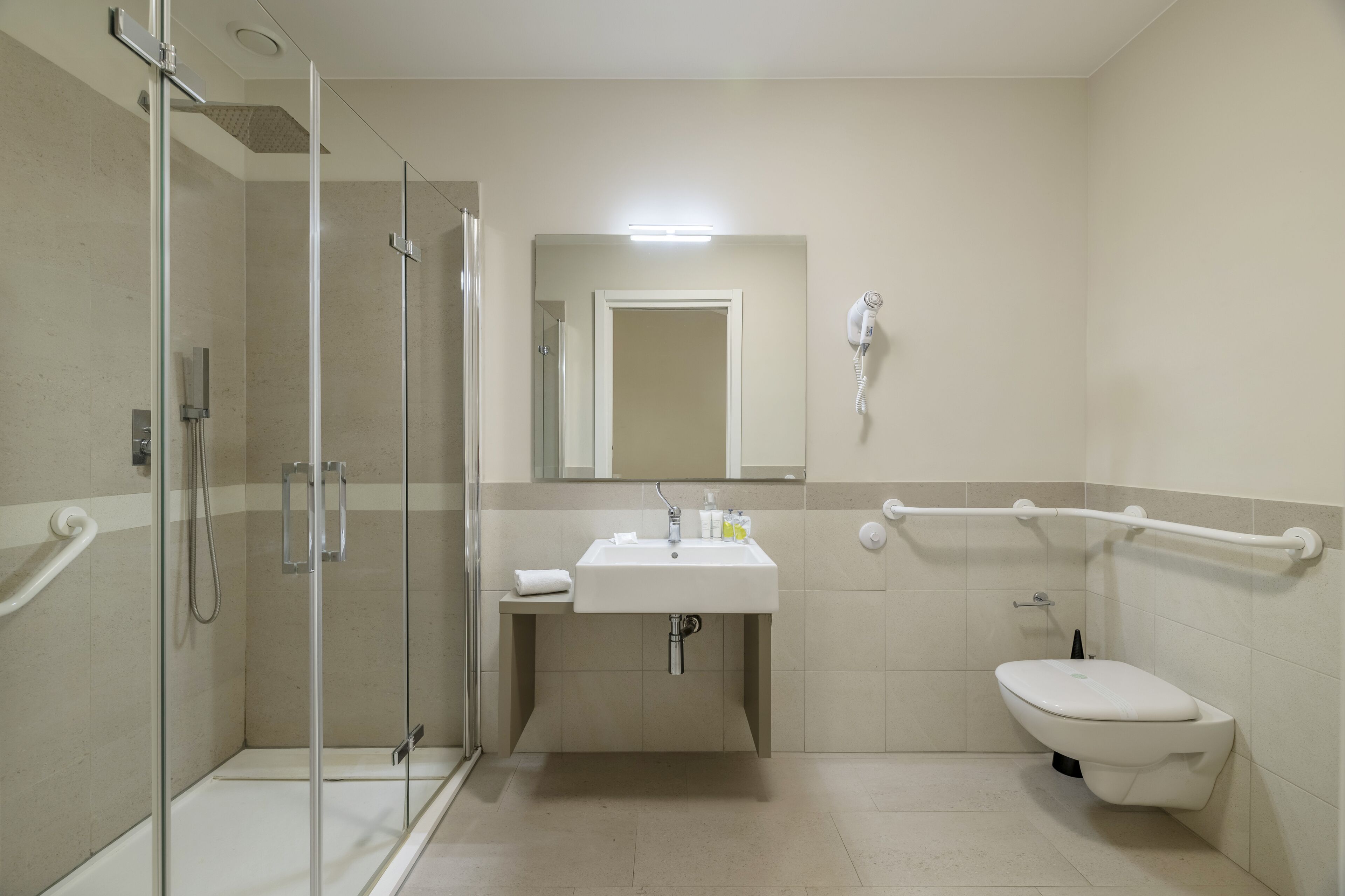 A modern bathroom with a glass-enclosed shower, a sink with a mirror above it, and a toilet.
