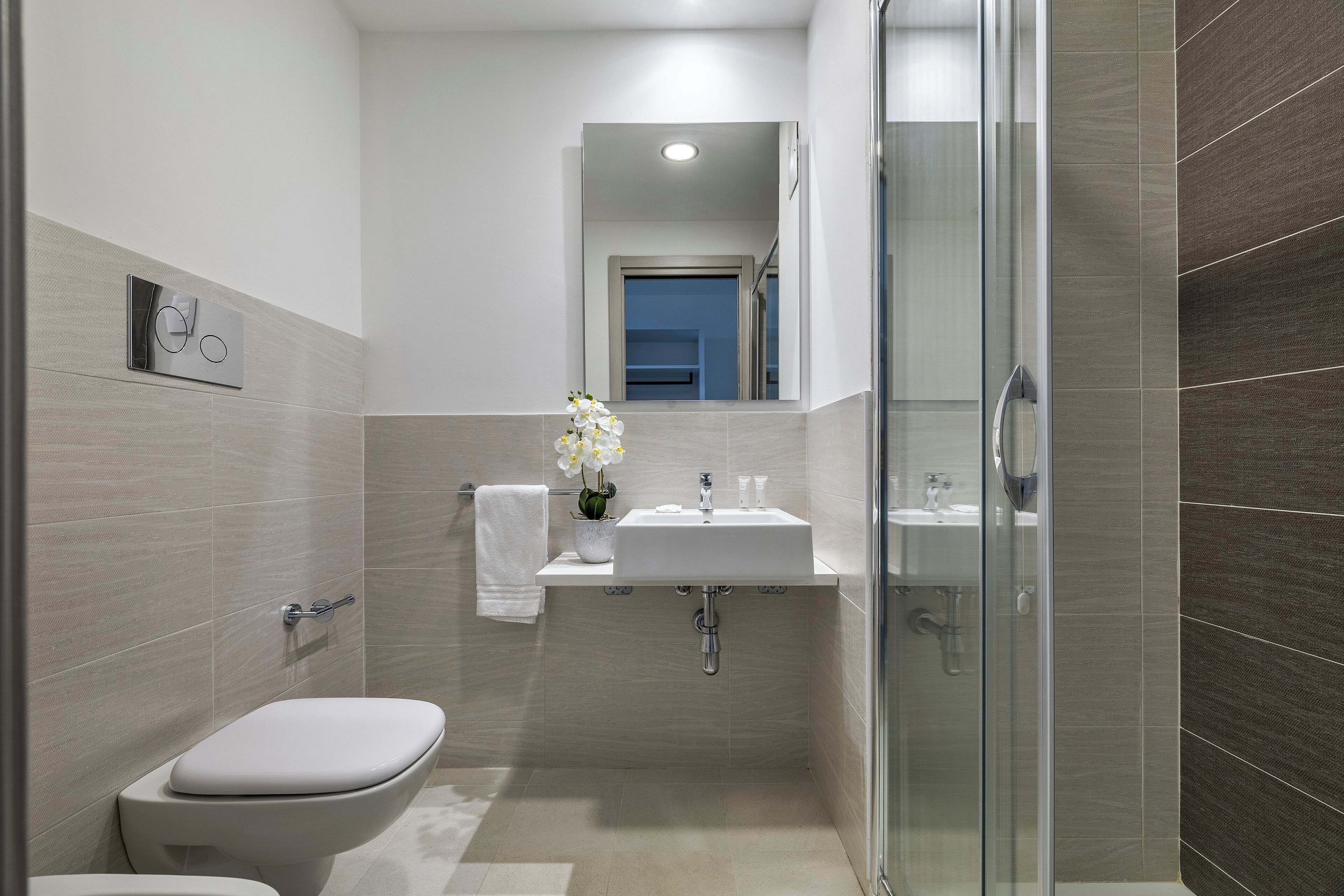 A modern bathroom with a toilet, sink, and shower.