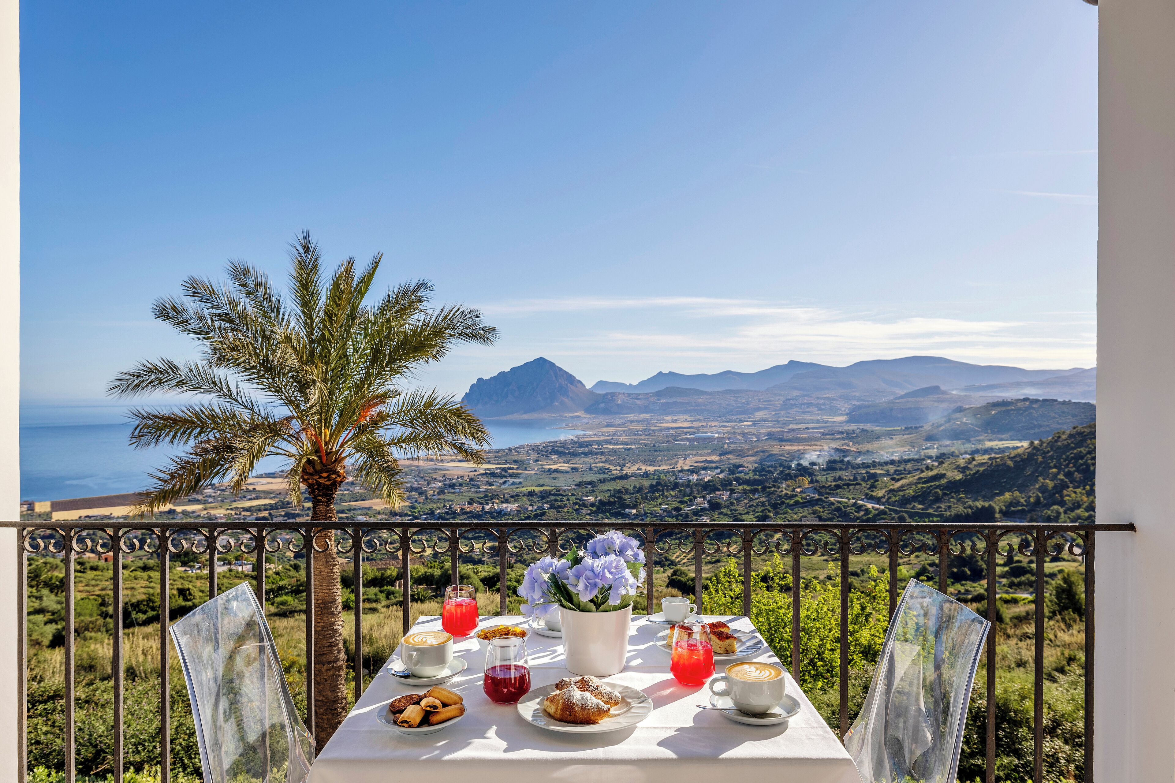 Une table dressée pour le petit-déjeuner, avec une vue imprenable sur les montagnes et la mer.