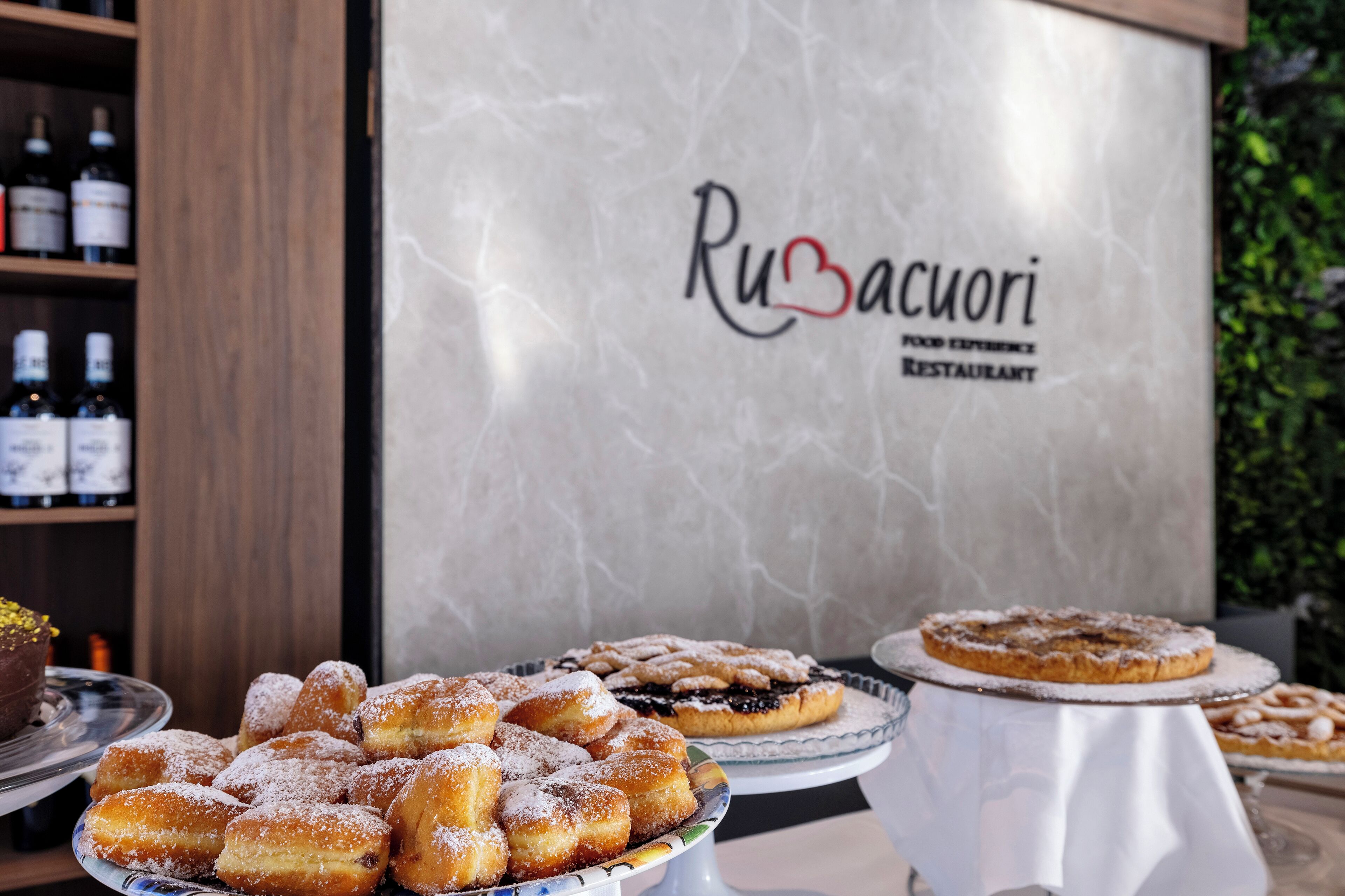 A dessert display with various pastries in front of a restaurant sign.