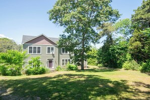 A two-story house with a front yard and a large tree.