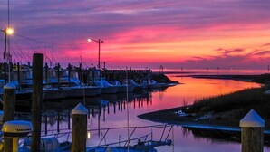 Ein Hafen im Abendlicht mit vertäuten Booten, einer Anlegestelle und ruhigem Wasser, das den Himmel spiegelt.