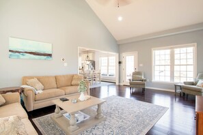 A spacious living room with a large window, a sofa, a coffee table, and a dining area.
