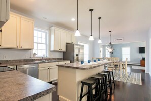 A kitchen with white cabinets, a granite countertop, and a central island with bar stools.