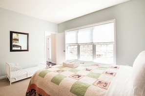 Quarto com cama, berço, janela com persianas e porta.