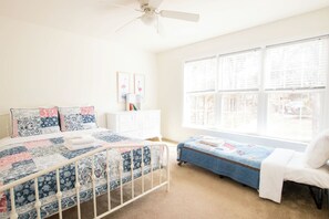 A bedroom with a bed, a nightstand, a window, and a ceiling fan.