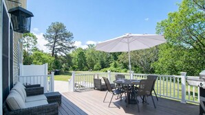 Eine Terrasse mit Gartenmöbeln, einem Grill und einem weißen Zaun.