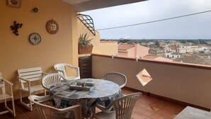 Ein Balkon mit rundem Tisch und Stühlen, Blumentöpfen und dekorativen Tellern an der Wand.