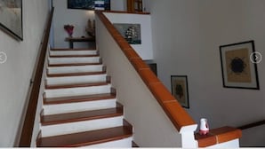 Eine Treppe mit Holzboden und einer weißen Handläufung führt zu einer Empore, auf der sich ein kleiner Tisch und Dekoration befinden.