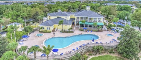 Um resort amplo com várias piscinas, uma área de praia e vista para o oceano.