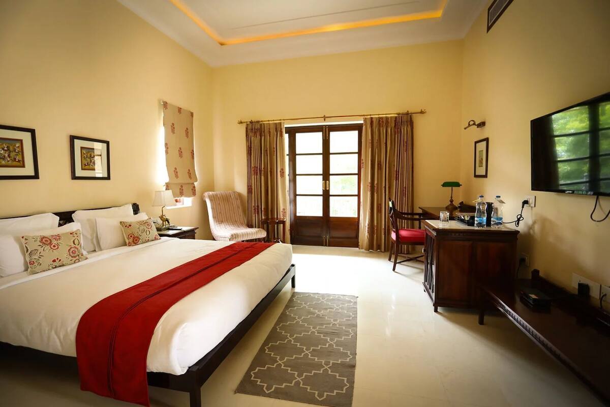 A hotel room with a large bed, a desk, a chair, a television, and a window with curtains.