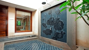 Een badkamer met betegelde vloer, een raam met houten zonwering en een muur met bloemenmural.