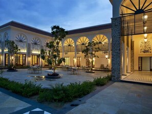 A building with a courtyard, featuring a covered seating area and a stone facade. - The Kipling Lodge (Sawai Madhopur)