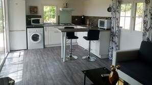 A compact kitchen with a washing machine, microwave, and a small dining area with two bar stools. - Secluded chalet with private access and panoramic views (Draguignan)