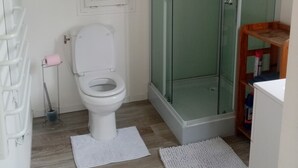 A bathroom with a toilet, a glass shower enclosure, a wooden shelf, and a white radiator. - Secluded chalet with private access and panoramic views (Draguignan)