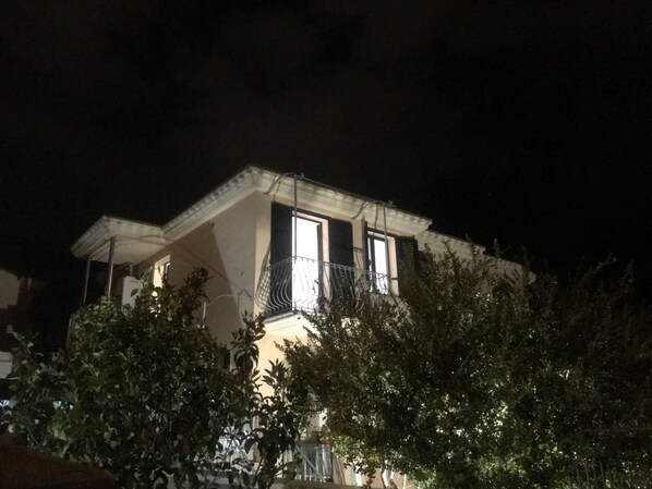A house with a balcony and a lit window at night.