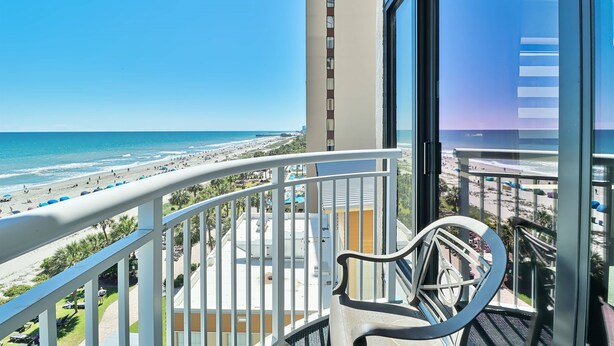 A balcony with a view of the beach and ocean.