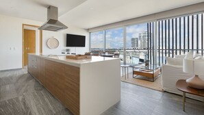 Eine moderne Küche mit Kochinsel, großem Fenster und Stadtblick sowie Essbereich mit Sofa und Tisch.