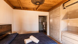 A bedroom with a wooden ceiling, a bed with a blue quilt, a white towel, and a wardrobe. - Welcome to Filippi Furnished Bungalows! (PORTO-VECCHIO)