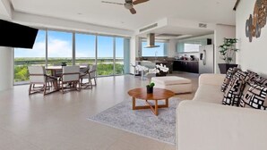 Una sala de estar moderna con un gran ventanal, un ventilador de techo, un comedor y una cocina.