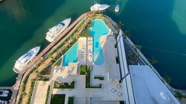 Luftaufnahme eines Resorts mit einem großen Schwimmbecken, mehreren vor Anker liegenden Booten und einer Marina.