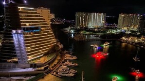 Ein modernes Hotel mit geschwungener Fassade, einer Marina mit Booten und einer Stadtkulisse im Hintergrund.