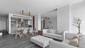 Ein modernes Wohnzimmer mit einer Couch, Hocker und Essbereich.
