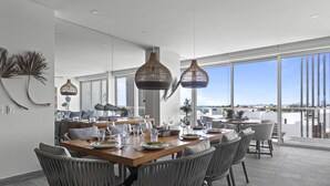A modern dining area with a wooden table set for six, surrounded by wicker chairs. - Spectacular 3BR Apartment/w Amazing Rooftop Views (Cancún)