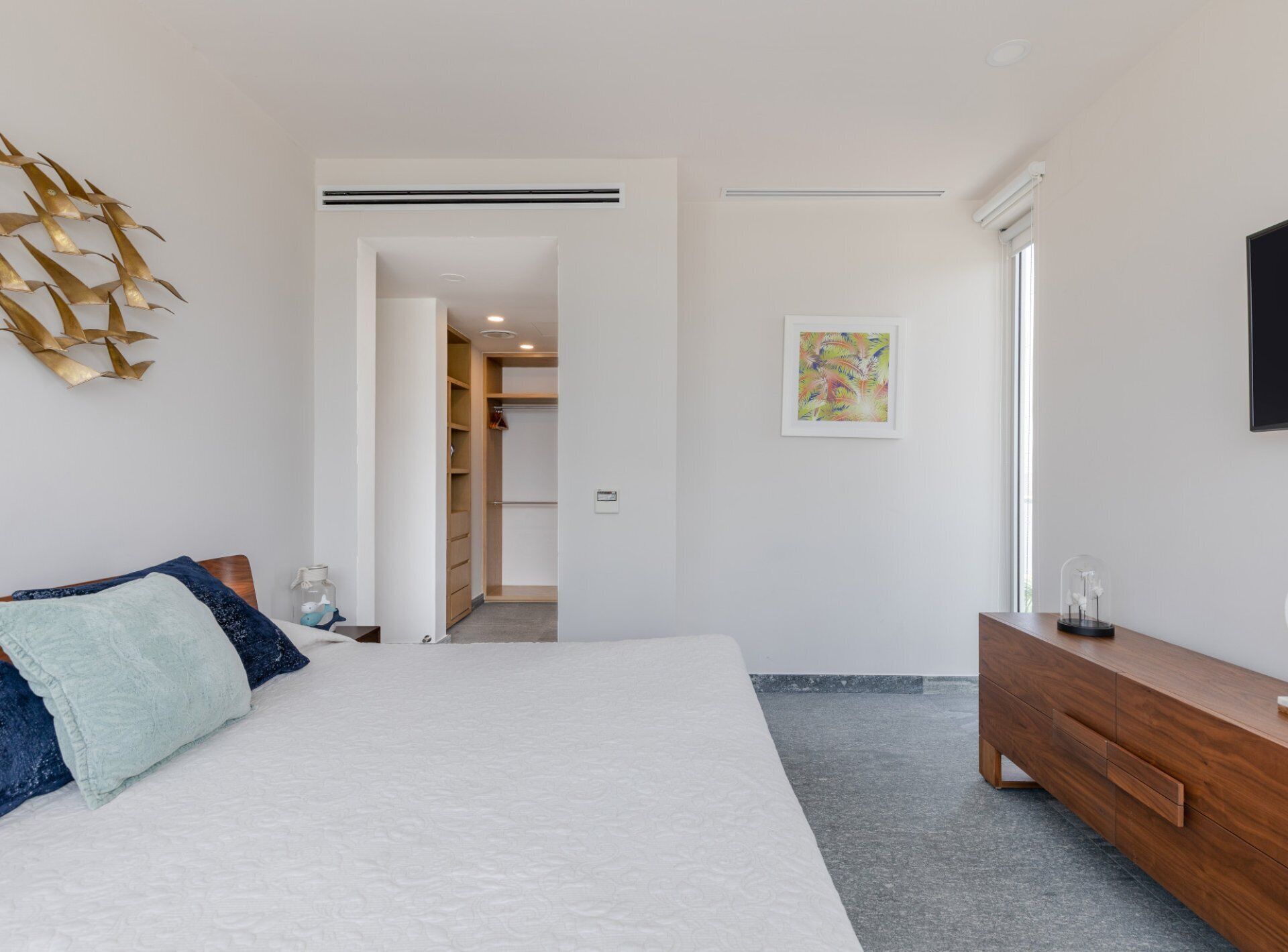 A bedroom with a bed, a wooden dresser, a closet, and a painting on the wall.