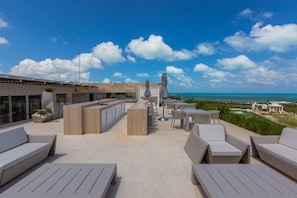 Terraço no telhado com área de estar ao ar livre, bar e vista para o oceano.
