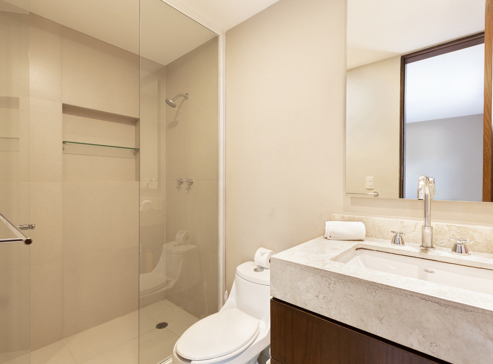 Une salle de bain moderne dotée d’une douche à parois de verre, de toilettes et d’un lavabo avec un plan de travail en marbre.