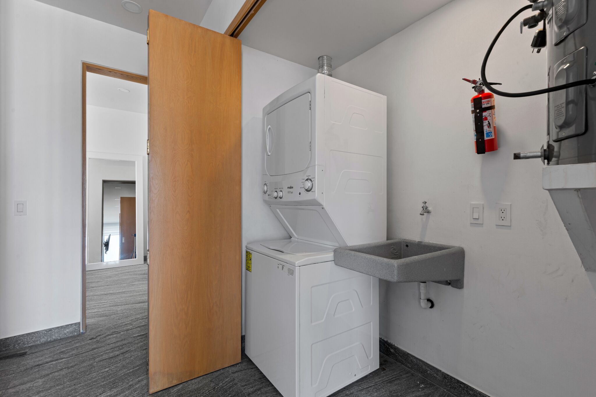 A laundry room with a washing machine, a sink, and a fire extinguisher.