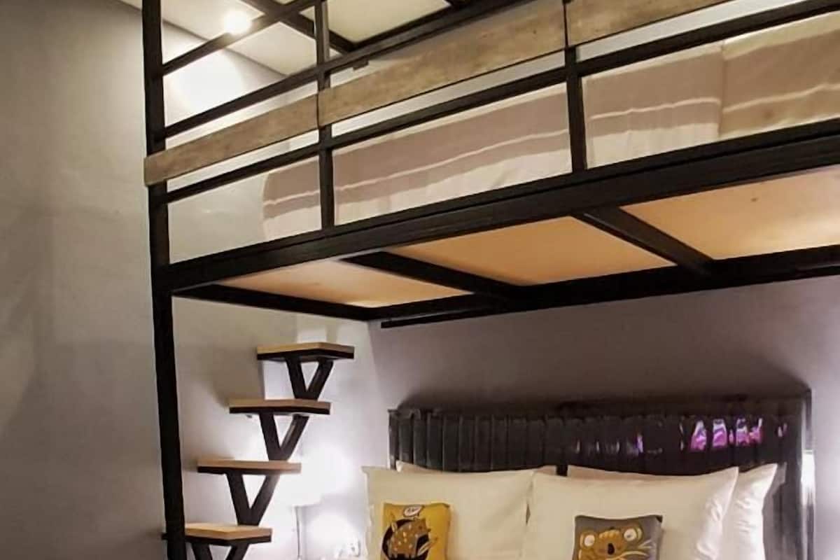 Uma cama beliche com cabeceira, travesseiros e cobertor.