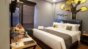 A hotel room with a bed, a table with a basket of fruit, a bottle of water, and a towel. - Nine Hotel Palembang (Palembang)