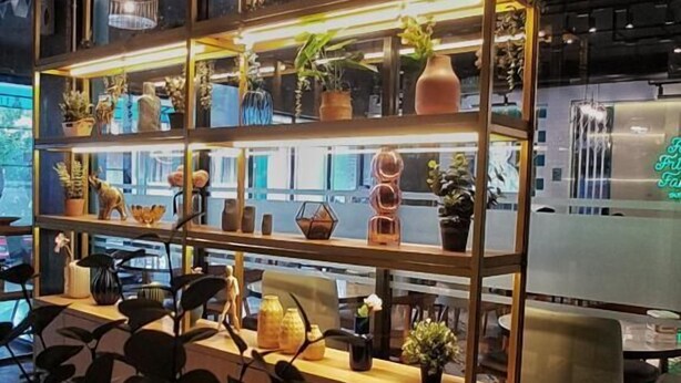 A modern interior with a multi-tiered wooden shelving unit displaying various decorative items and plants. - Nine Hotel Palembang (Palembang)