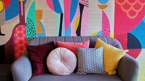 A room with a colorful abstract mural, a grey sofa with patterned cushions, and a geometric patterned floor. - Nine Hotel Palembang (Palembang)